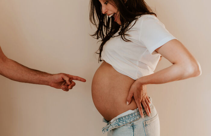 Schwangere Frau mit sichtbarem Babybauch – Kosten von Schwangerschaft und Geburt überrascht